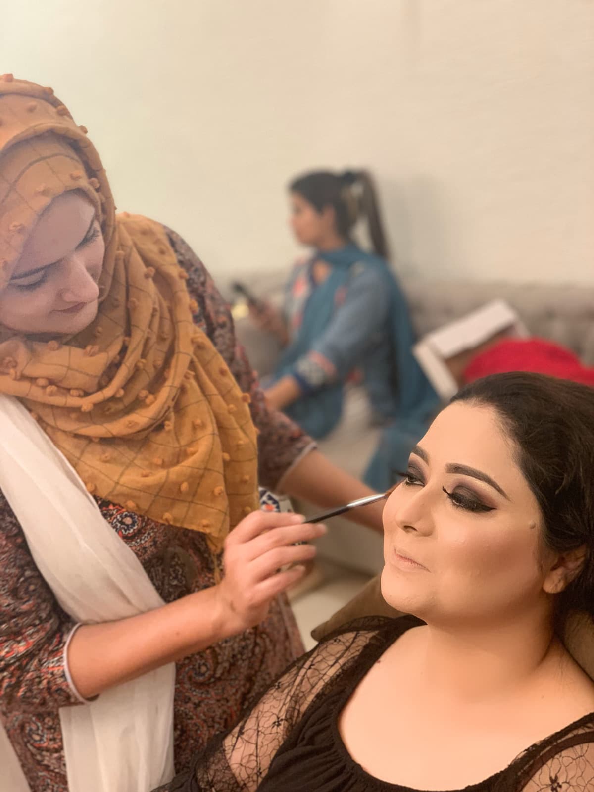 Shehwar perfecting a client's eye makeup